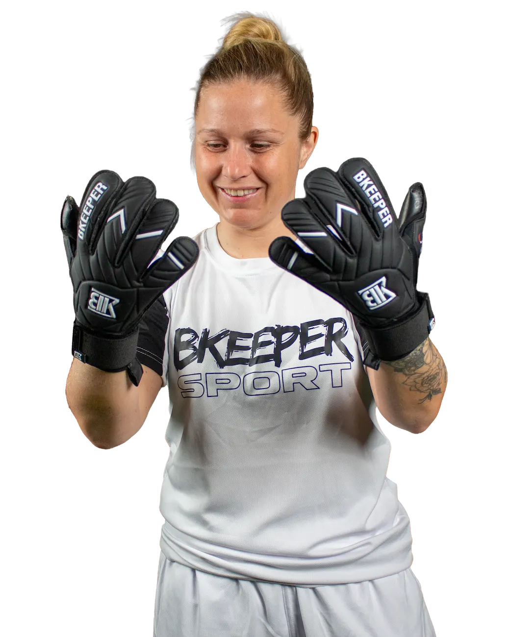 A woman wearing black goalkeeper gloves with white and gray accents, posing with both gloves raised in front of her face. She is wearing a white Bkeeper Sport athletic shirt and light gray shorts against a solid white background.