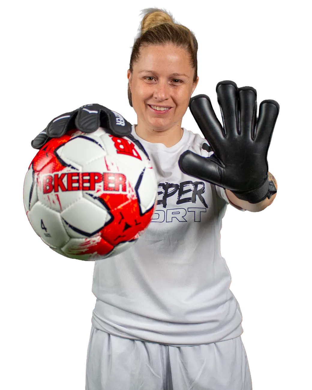A smiling female soccer goalkeeper wearing a white goalkeeper jersey and gloves, holding a red, white, and black soccer ball. The background is solid white.
